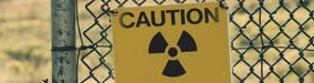 chainlink fence with yellow sign with hazardous symbol and the word 'caution' written on it hanging on the fence